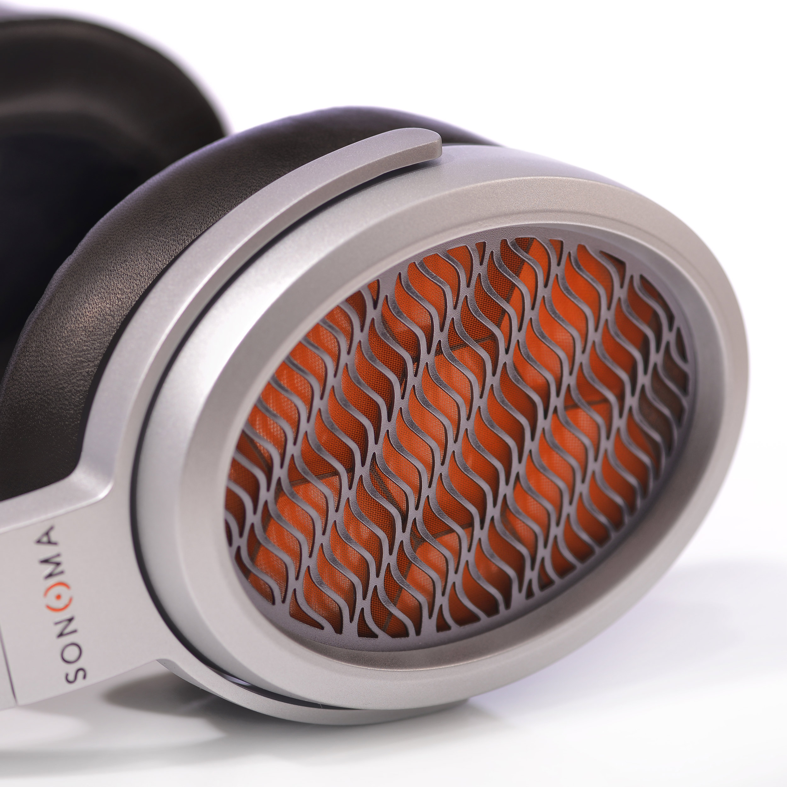 Oval shaped, injected magnesium silver earcups with orange honeycomb HPEL visible through a wavy metal mesh